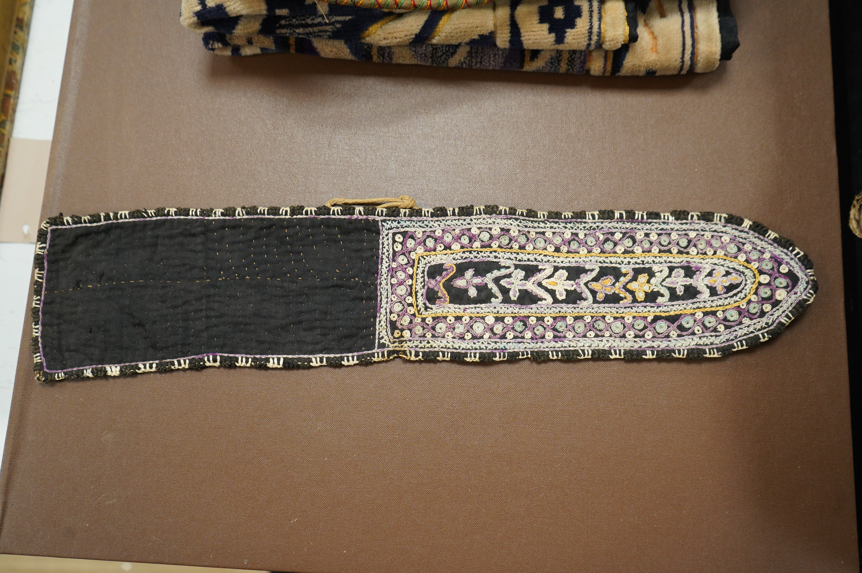A collection of 20th century textiles to include: child's cream and gold embroidered waistcoat, a metallic embroidered bag, a leather embroidered bag, two Art Deco printed velvet cushion covers, a cotton quilted runner a